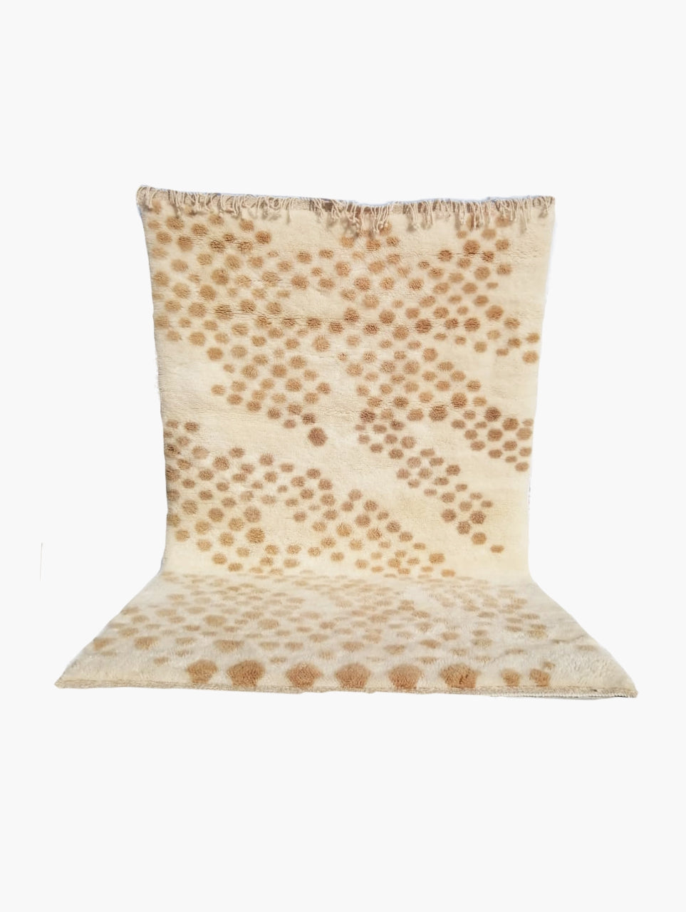 A folded beige rug with a whimsical pattern consisting of what appears to be stylized leaves or foliage in a earthy tone.